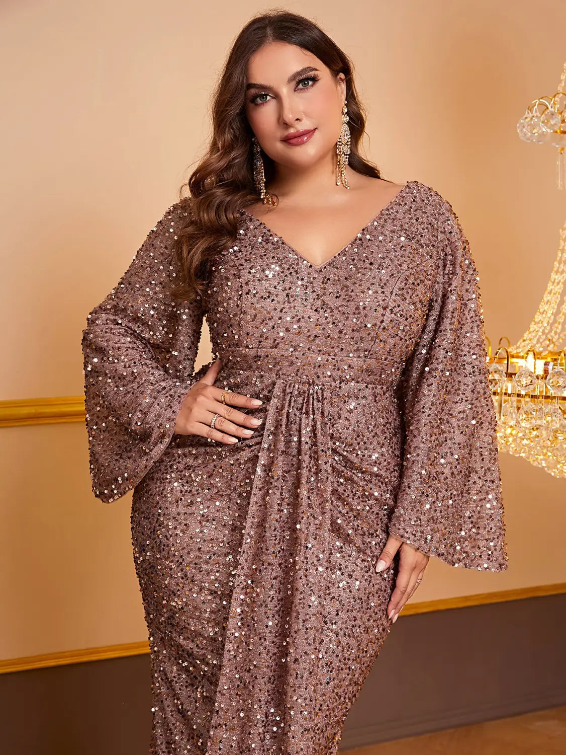 a rose gold sequin long sleeved evening gown with a v-neckline and bell sleeves made from shimmering sequined fabric