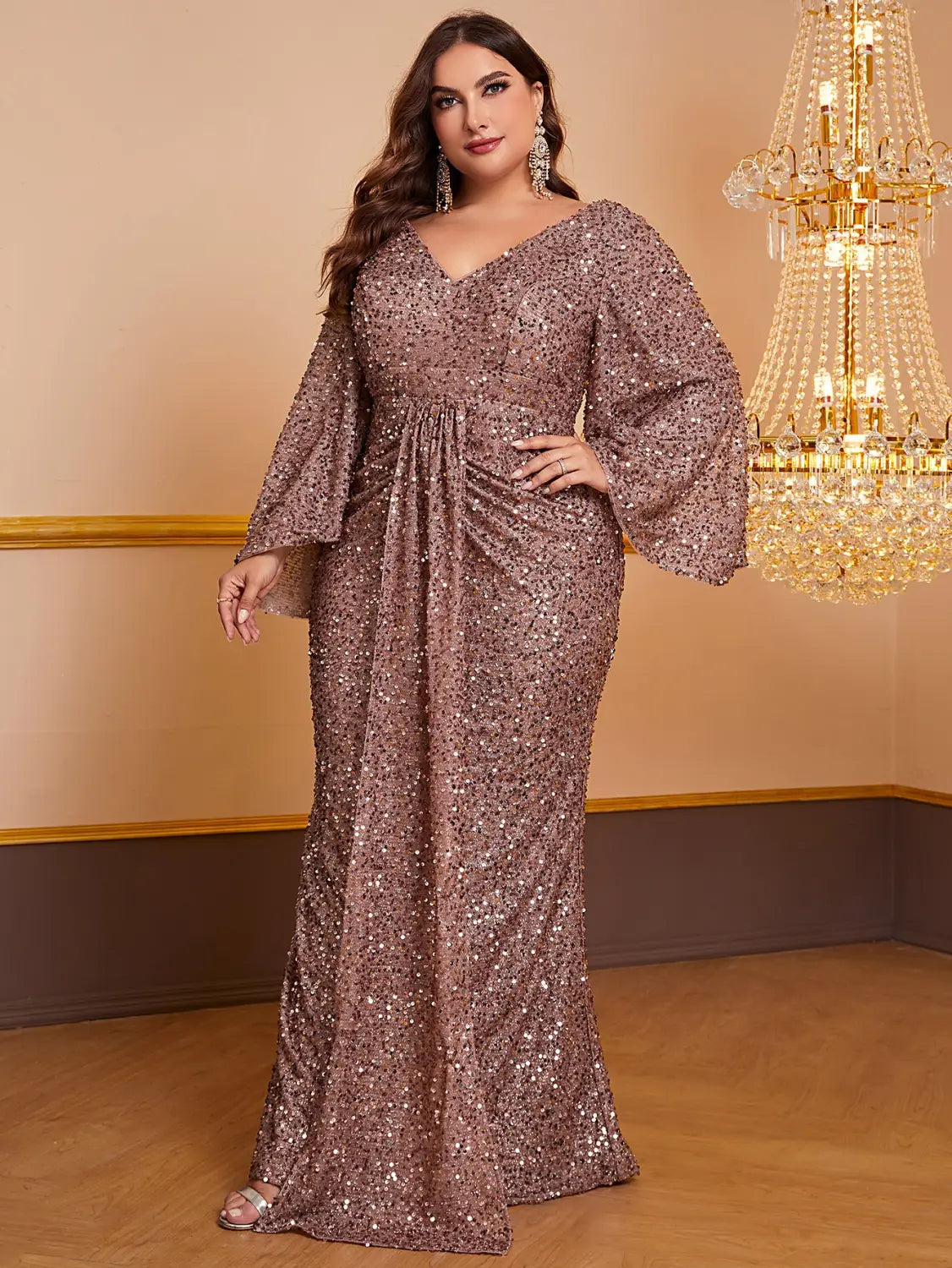 A shimmering rose gold sequin long sleeved gown with a v-neckline and bell sleeves.