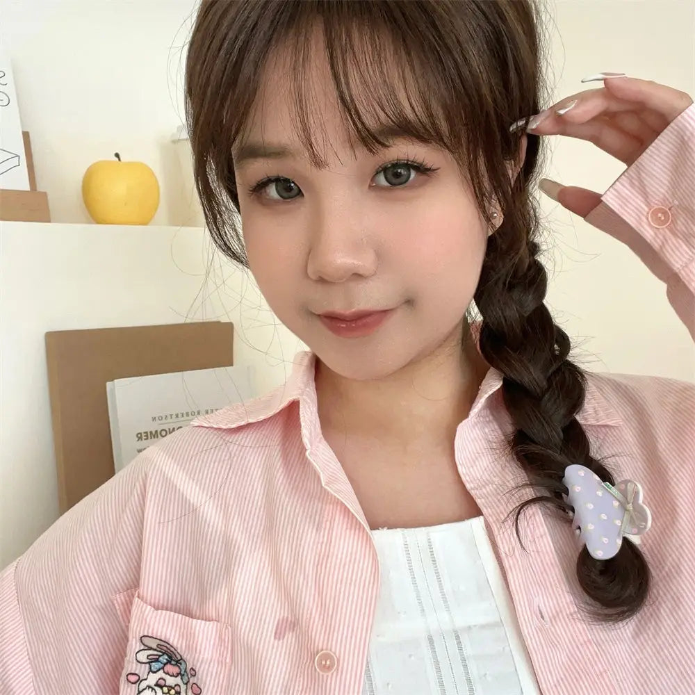 a light pink striped button-up shirt featuring a cartoon character patch on the pocket paired with a pink butterfly floral small jaw clip with bow for secure styling using the jaw clip grip