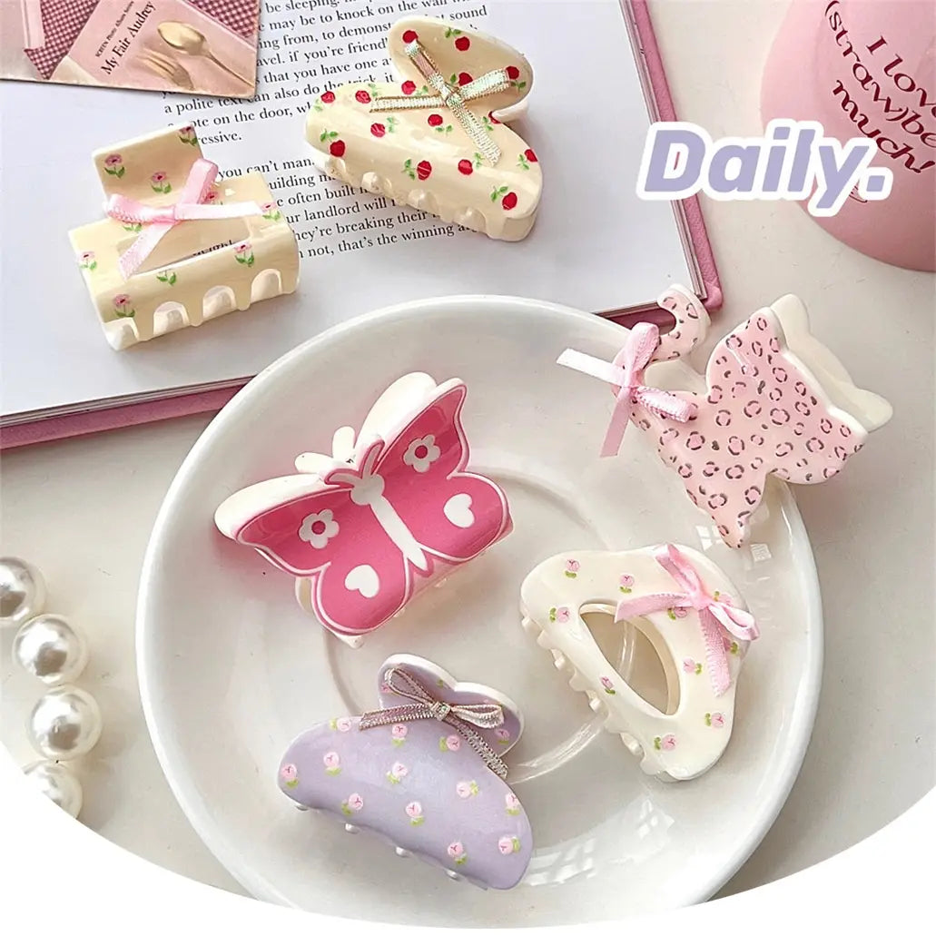 Pastel-colored pink butterfly small jaw clip with floral and polka dot patterns and delicate bow detail featuring a secure jaw clip grip.