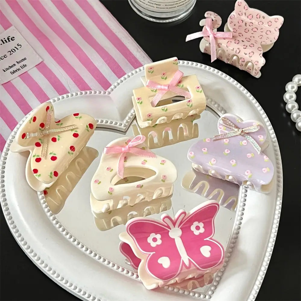pastel-colored pink butterfly floral small jaw clip and bow made of glossy plastic with delicate floral patterns and a secure jaw clip grip for styling hair.