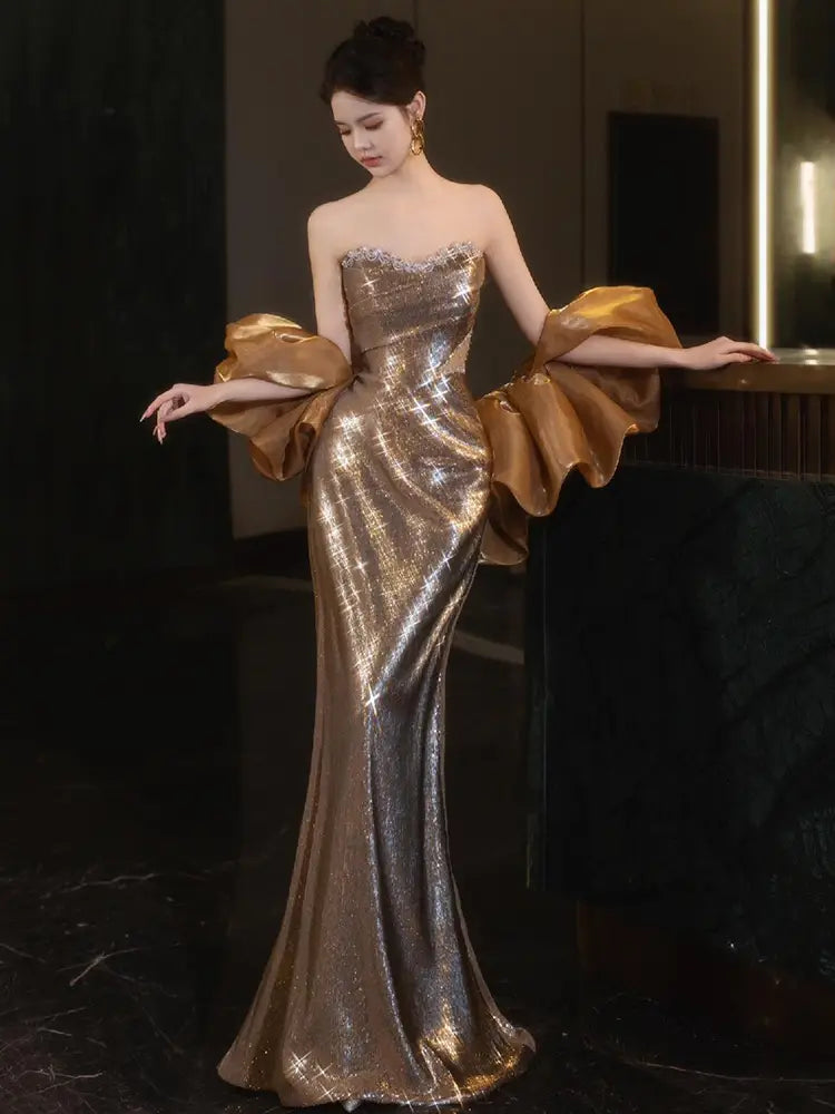 A shimmering gold sequined mermaid gown with dramatic voluminous sleeves perfect for a niche banquet temperament evening dress.