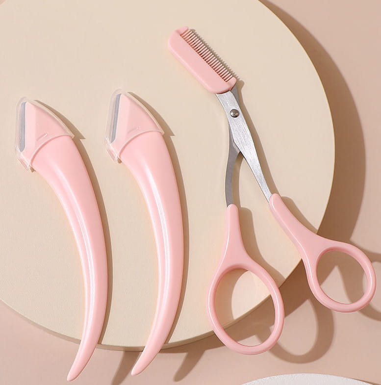 Set of three pink plastic eyebrow trimming knives with metallic blades and a matching pink-handled comb scissors for precise eyebrow trimming and grooming.