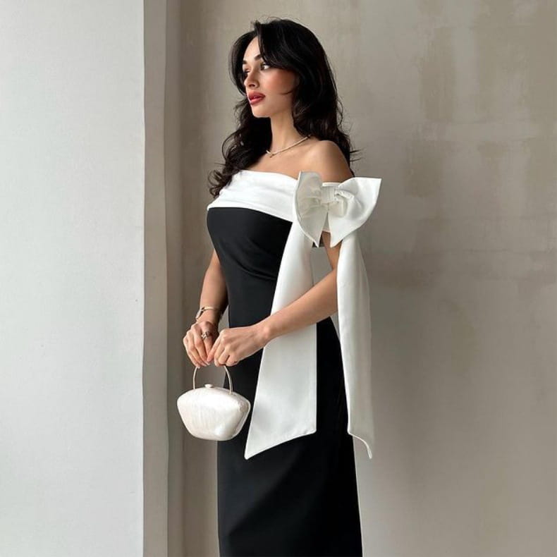 a sleek white satin mini handbag with a rounded shell-like shape and delicate metal handle complementing an off-shoulder color matching elegant cocktail dress