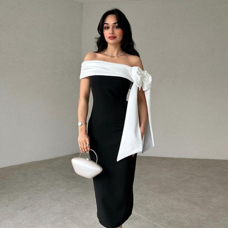 off-shoulder color matching elegant cocktail dress featuring a black and white design with a flowing white fabric bow on the shoulder for a matching elegant cocktail look