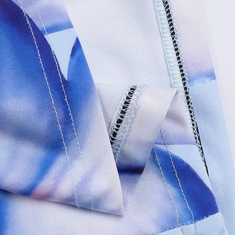 a pink floral american style flower strap dress shown with a soft blue and white tie-dye patterned fabric featuring visible stitching along the seams