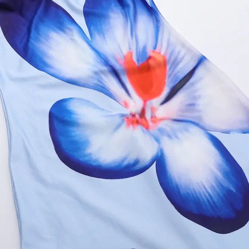 light blue fabric of an american style flower strap dress featuring a large stylized flower print with deep blue petals and a vibrant orange center