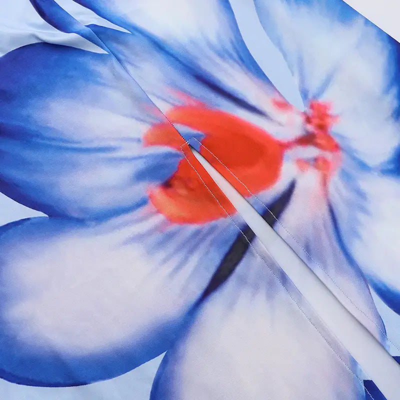 a delicate silver chain rests on vibrant blue and orange floral fabric of a pink floral american style flower strap dress