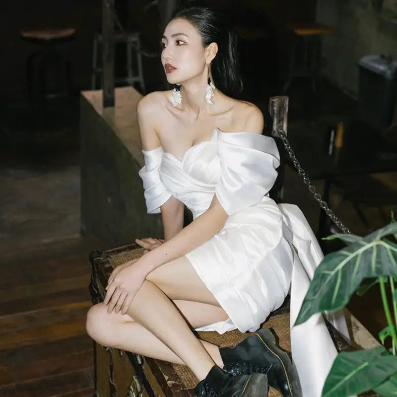 White satin off-the-shoulder short model color engagement dress with voluminous puffed sleeves and a flowing train.