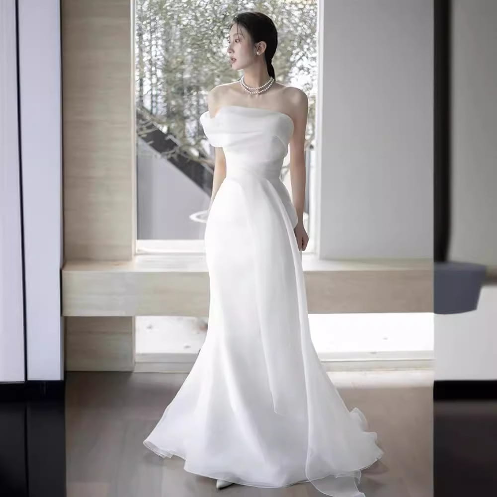 A flowing white satin off-shoulder wedding dress with a fitted bodice and flared skirt designed as a light wedding dress for the bride.