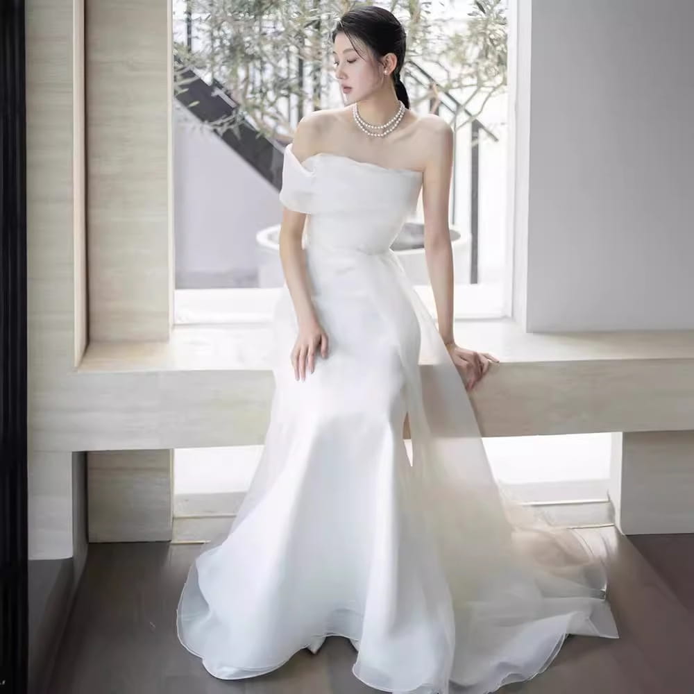 off-shoulder satin light wedding dress featuring a flowing white mermaid-style silhouette with a fitted bodice and sheer overlay suitable for a wedding dress bride.