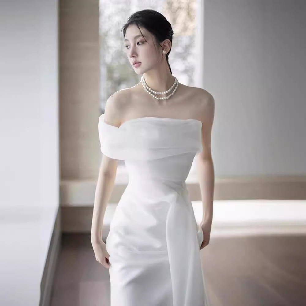 A flowing white off-shoulder satin wedding dress with a fitted silhouette and soft draping details perfect for a light wedding dress bride.