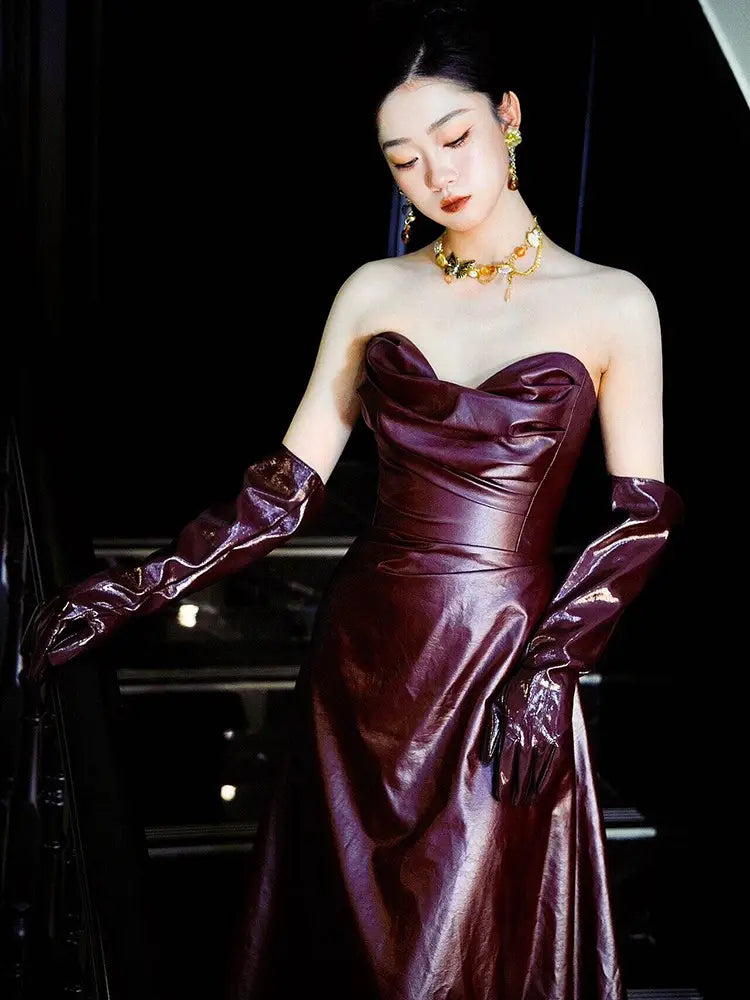 A glossy burgundy leather strapless leather skirt evening gown with long matching gloves designed for formal occasions.