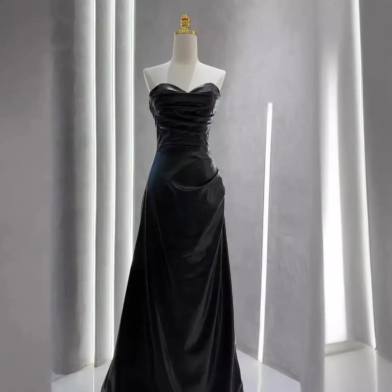 black satin strapless evening gown with a fitted bodice and flowing skirt paired with a burgundy leather skirt evening gown with sleeves.