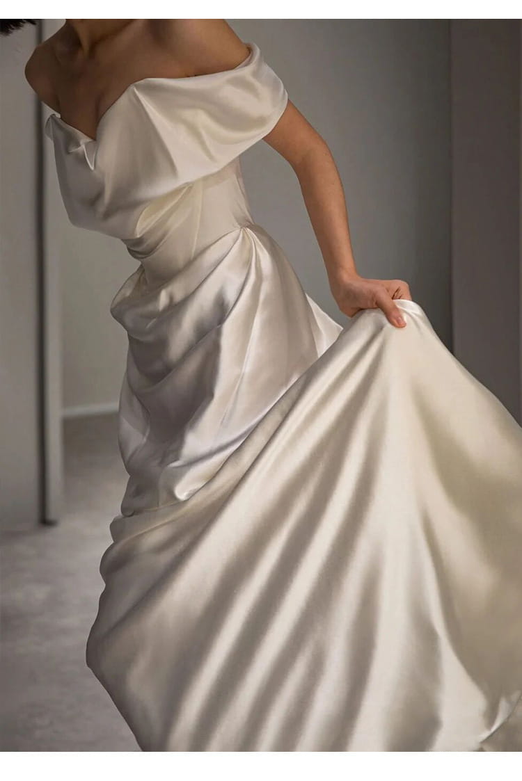 a flowing off-shoulder french white satin wedding dress with a fitted bodice and voluminous skirt perfect as a light wedding dress