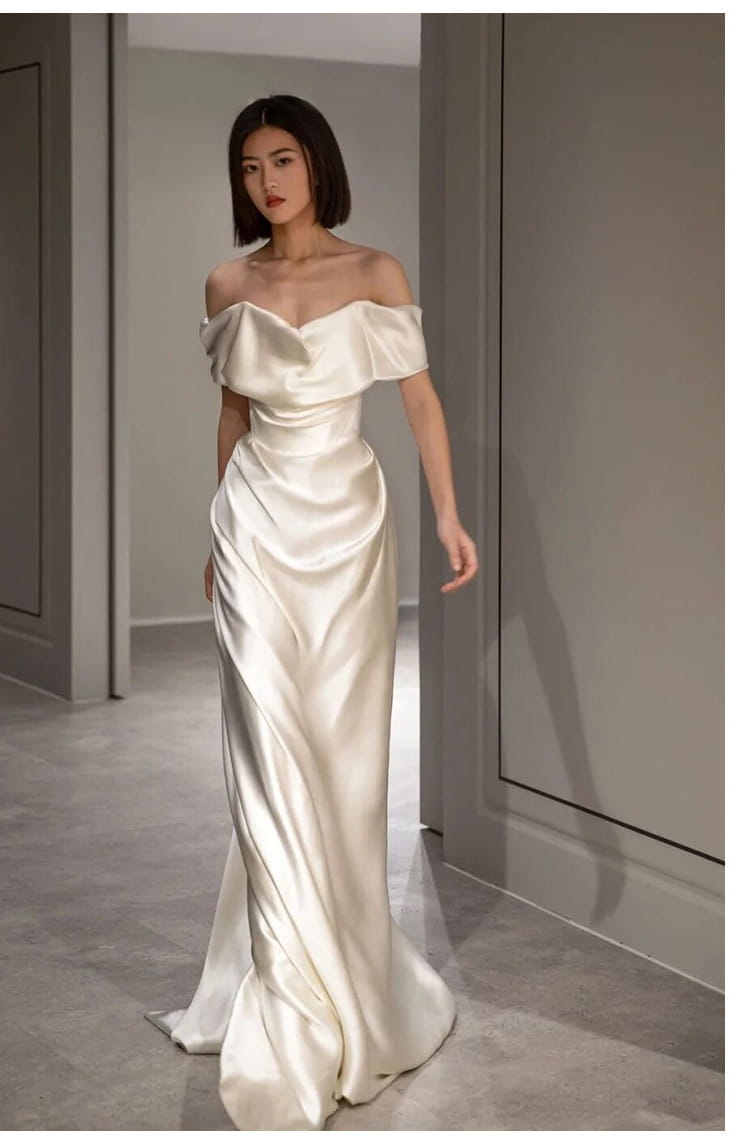 French white off-shoulder satin wedding dress in a soft ivory hue with elegant draping and a fitted silhouette perfect as a light wedding dress.