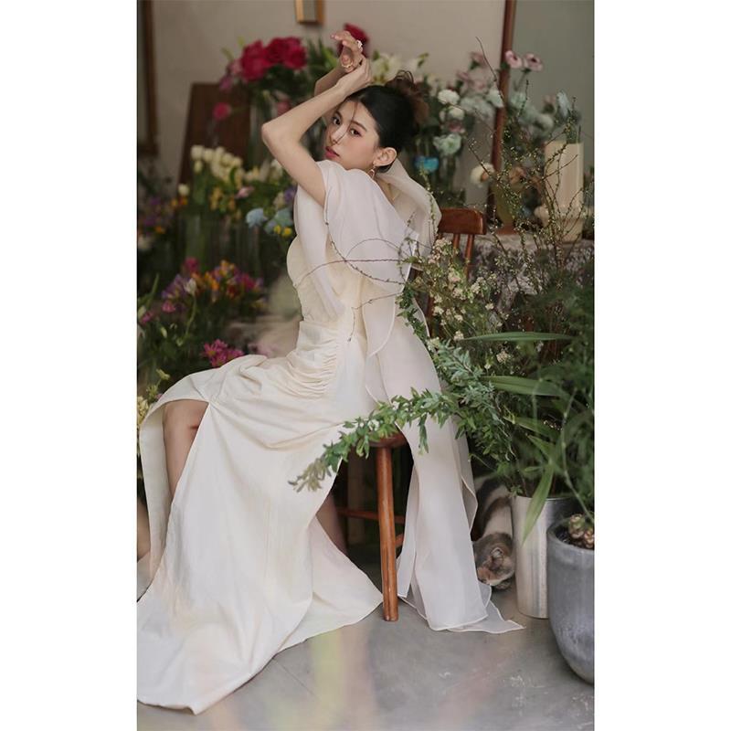 Ivory satin outdoor travel shooting light yarn gown featuring a flowing off-white fabric with a high slit and delicate sheer overlay.