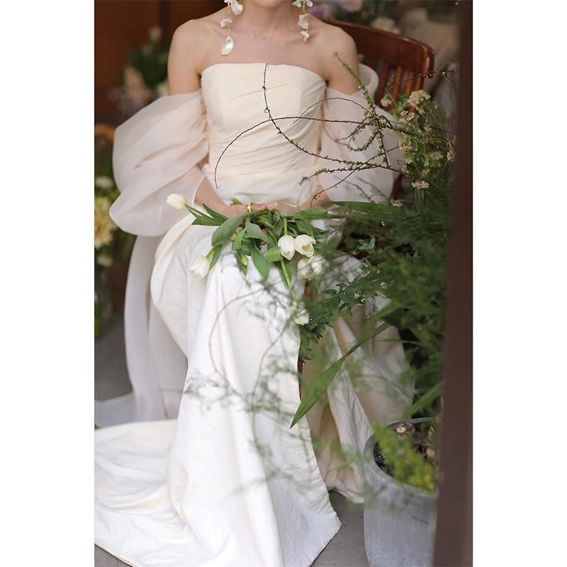 off-the-shoulder ivory satin wedding gown with voluminous puffy sleeves and flowing skirt designed for outdoor travel shooting and travel shooting light yarn use.