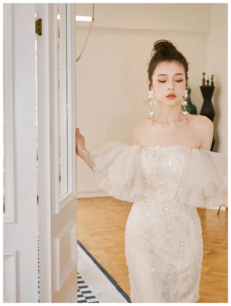 a shimmering off-the-shoulder ivory lace cinched waist miniskirt fairy dress featuring delicate beading and voluminous ruffled sleeves