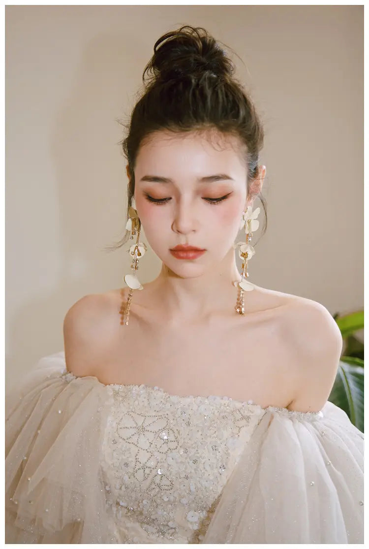 a woman wears an ivory lace cinched waist miniskirt fairy dress featuring an off-the-shoulder design with intricate silver beading and layered tulle sleeves