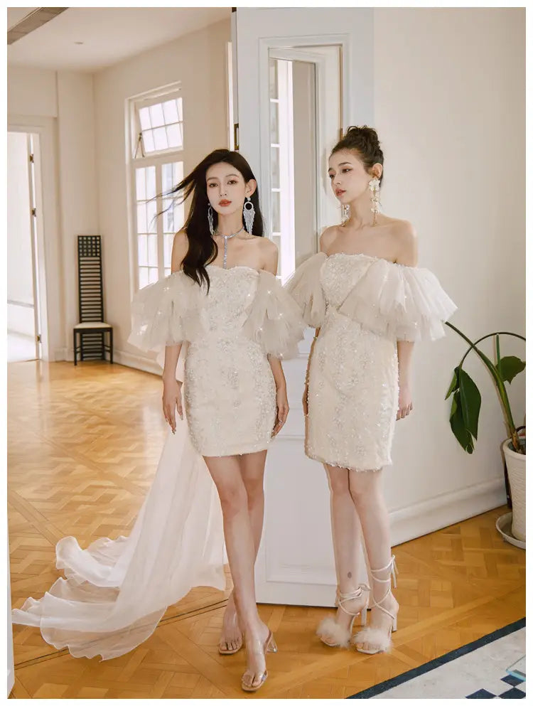 Elegant ivory lace cinched waist miniskirt fairy dress featuring off-the-shoulder design, voluminous sheer puff sleeves, and delicate beading.
