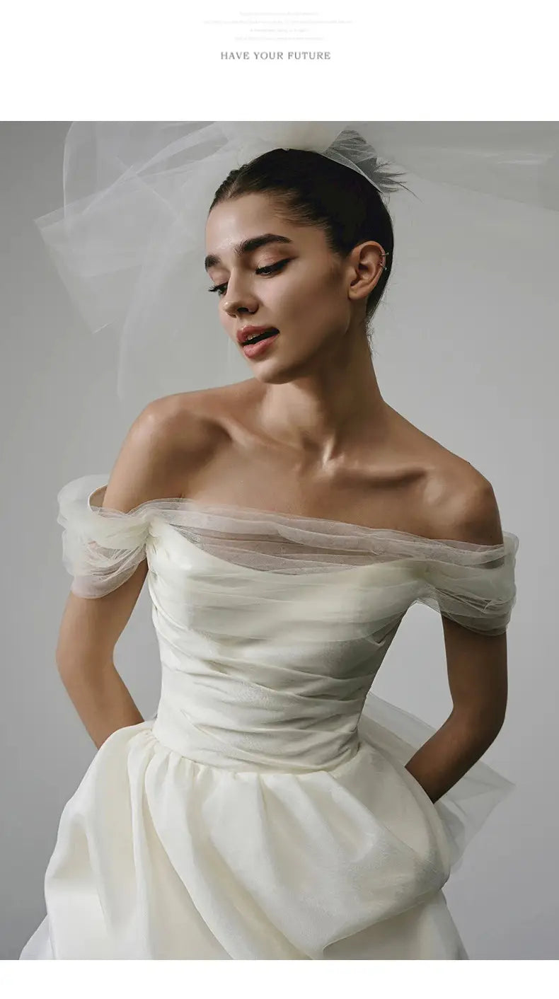 Off-shoulder tulle white wedding dress with a train featuring a fitted bodice, sheer tulle sleeves, and satin fabric, ideal as a light wedding dress.