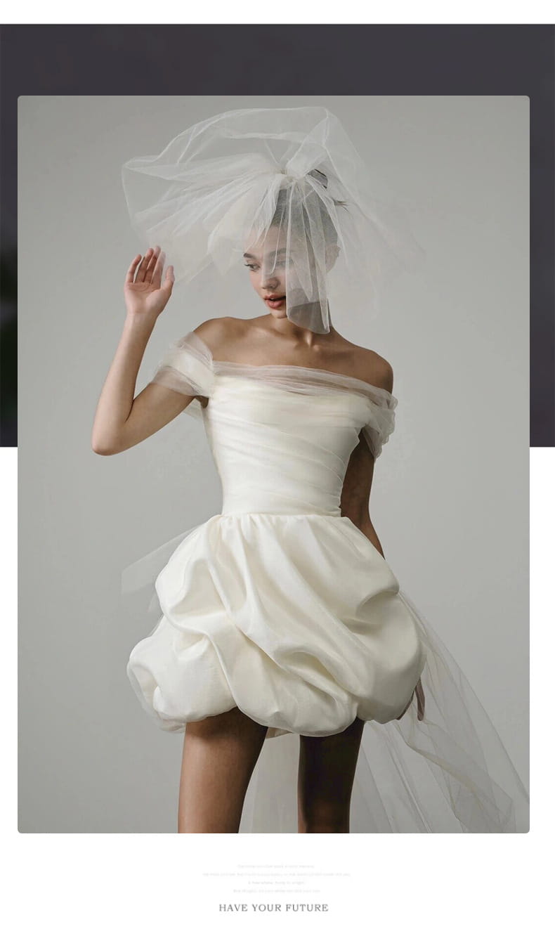off-shoulder tulle white wedding dress featuring a light wedding dress design with a white satin mini skirt, puffed silhouette, and matching sheer veil.