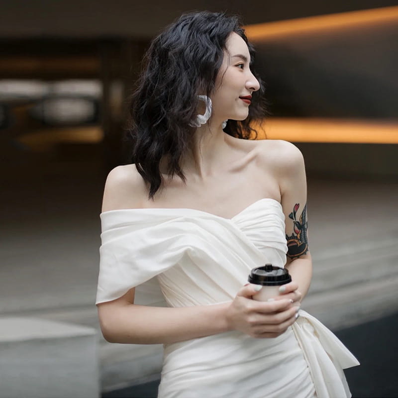 White off-the-shoulder light wedding gown short for women featuring a ruched bodice and flowing skirt in a draped mini dress style.