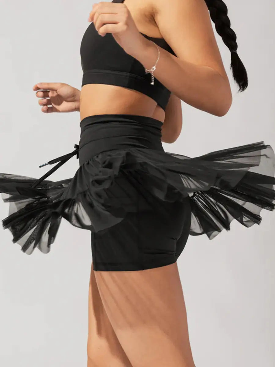 black sheer tulle skirt with fitted waistband and side ties shown alongside white high waist pleated skirt with safety pants summer design