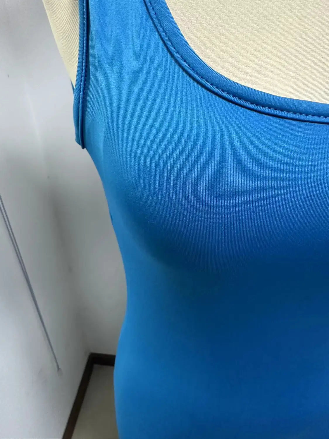 Bright blue women sleeveless flare tank top with smooth knit fabric and simple rounded neckline designed for fitness and yoga.
