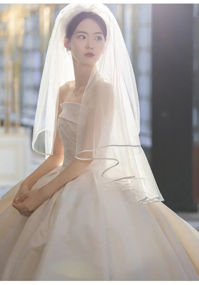 a flowing white bridal veil with delicate sheer fabric and subtle silver trim accents complements the simple elegant french satin wedding dress