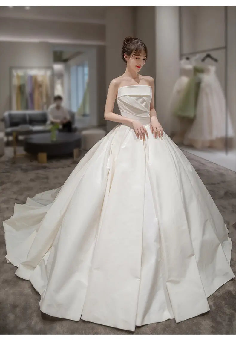 simple elegant french style strapless white satin wedding dress with a fitted bodice and an expansive flowing ballgown skirt