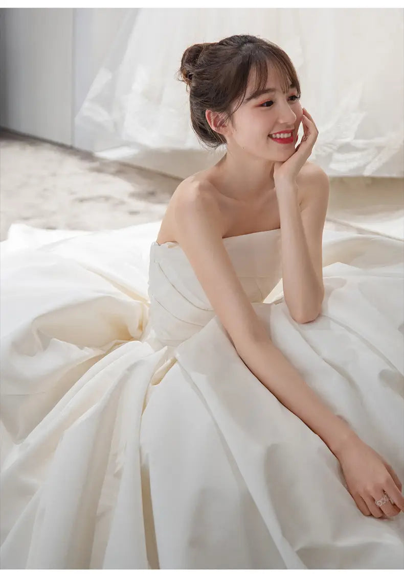 a simple elegant french style strapless white satin wedding gown with a full skirt and subtle ruching at the waist