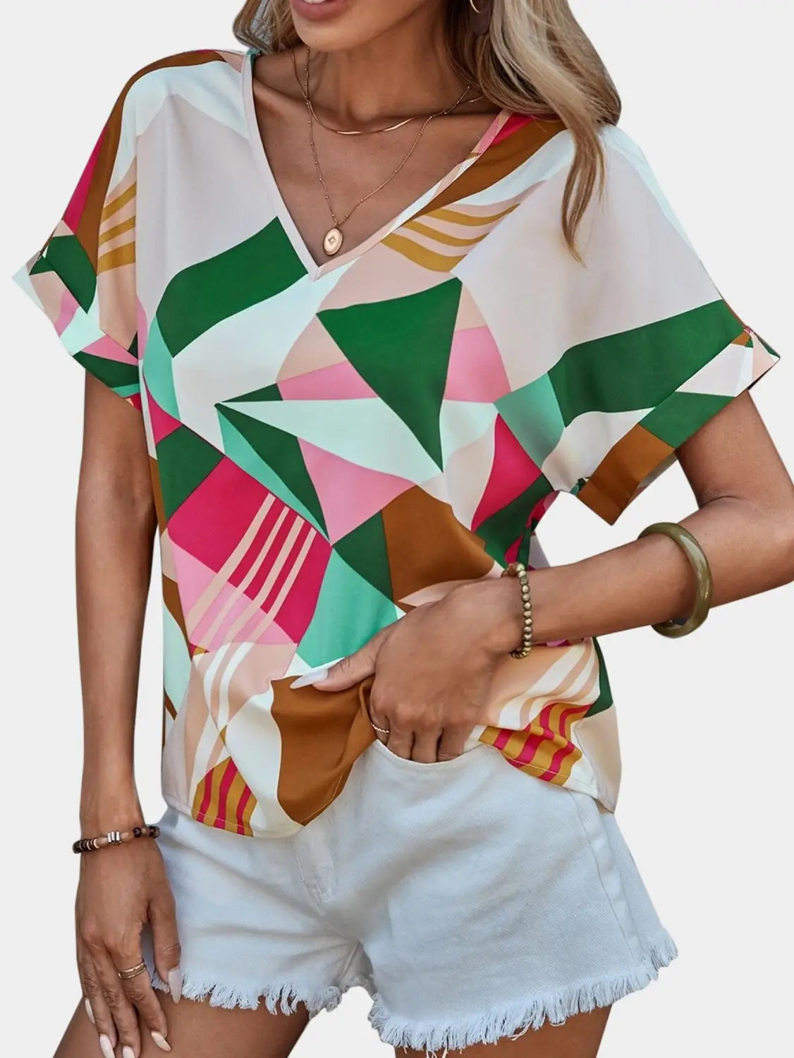 a vibrant women’s clothing printed short-sleeve top featuring a geometric pattern in shades of green pink and brown with a clothing printed v-neck design