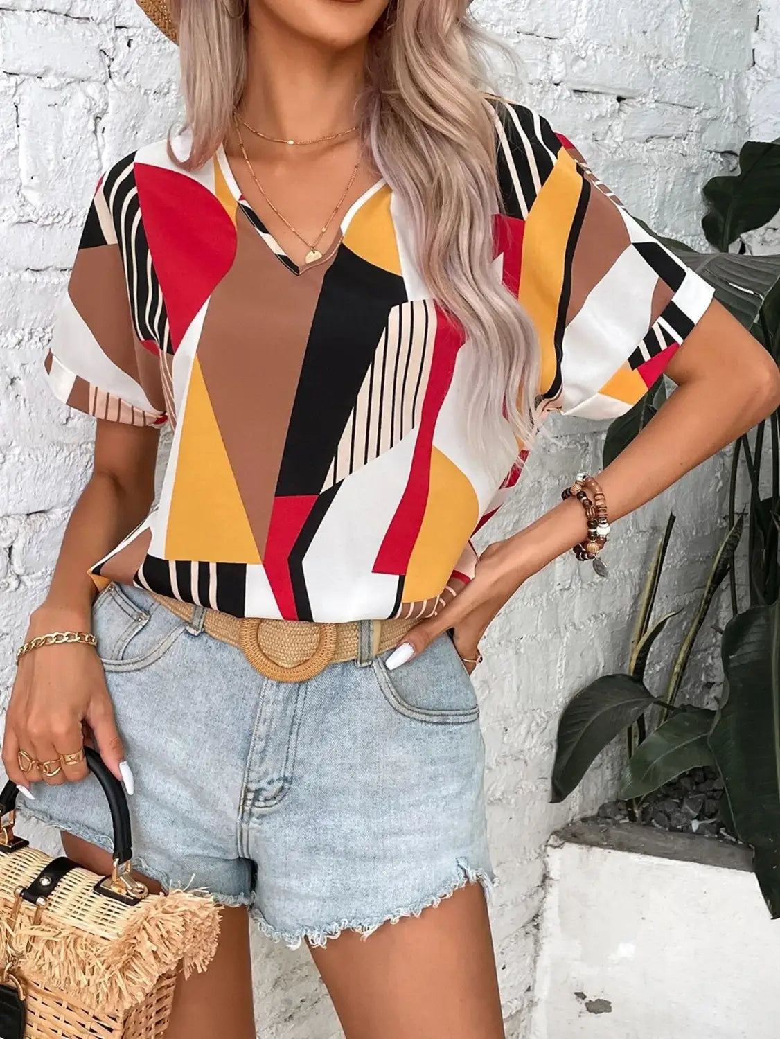 abstract geometric patterned short-sleeve clothing printed v-neck top for women in bold red yellow black white and brown tones