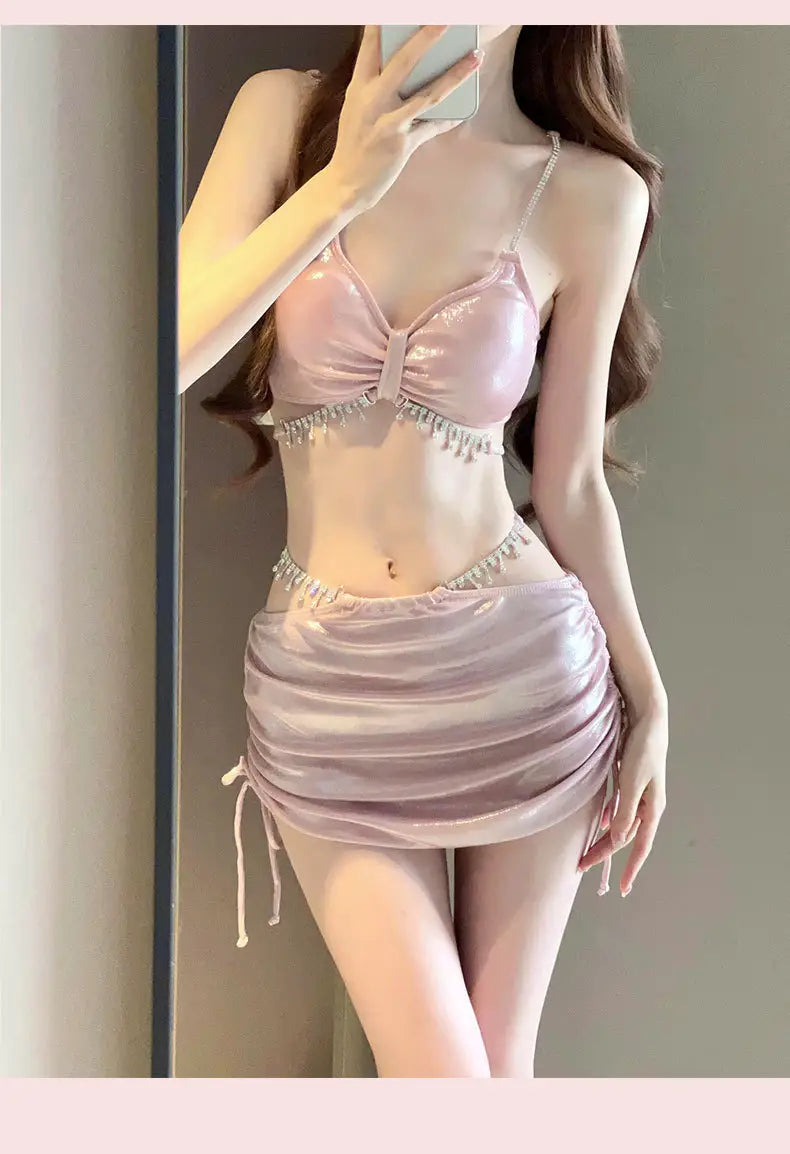 A shimmering pink satin bikini swimsuit top with a bow detail and crystal embellishments designed for luxury women’s fashion and plus size dresses bikinis.