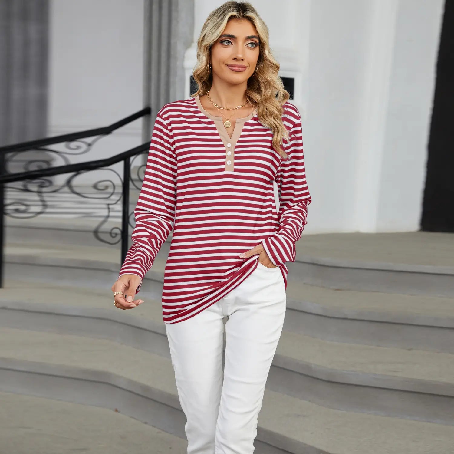 A women’s v-neck striped loose long-sleeved henley top with red and white horizontal stripes, a three-button neckline, and a side slit.