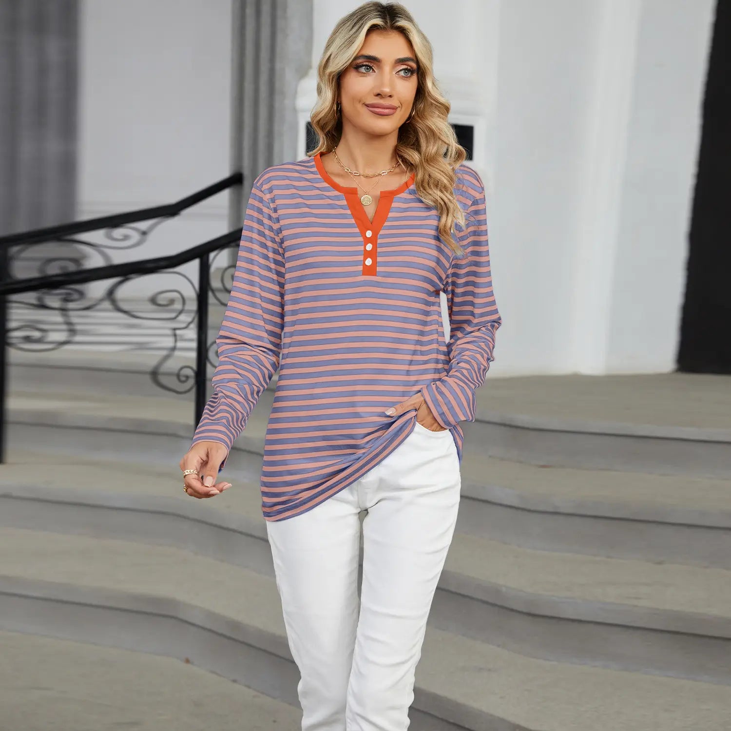 women’s v-neck striped loose henley top with long sleeves featuring soft lavender and muted pink horizontal stripes and a contrasting orange collar and placket with three matching buttons.