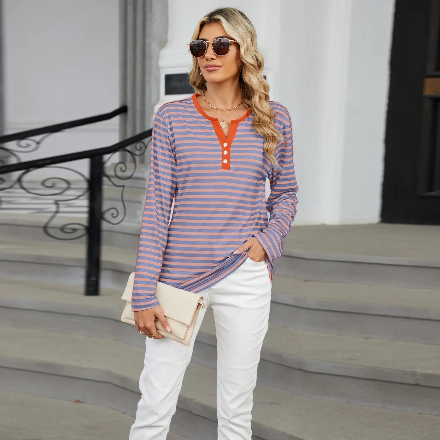 a woman wears a women’s v-neck striped loose henley top with long sleeves and three buttons in lavender and orange stripes