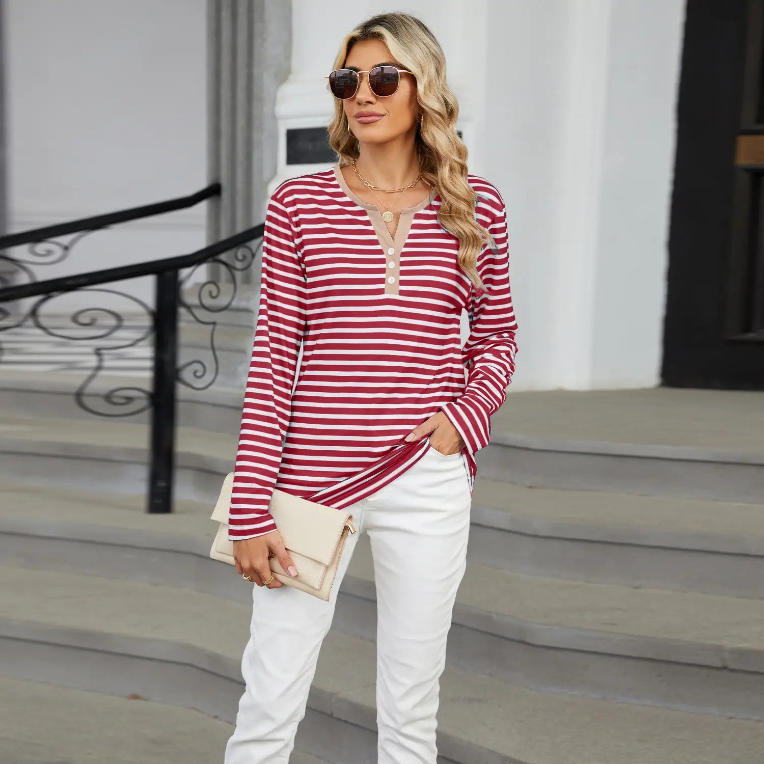 A woman wears a long-sleeved red and white horizontally striped loose henley top with a v-neck and three buttons at the neckline.