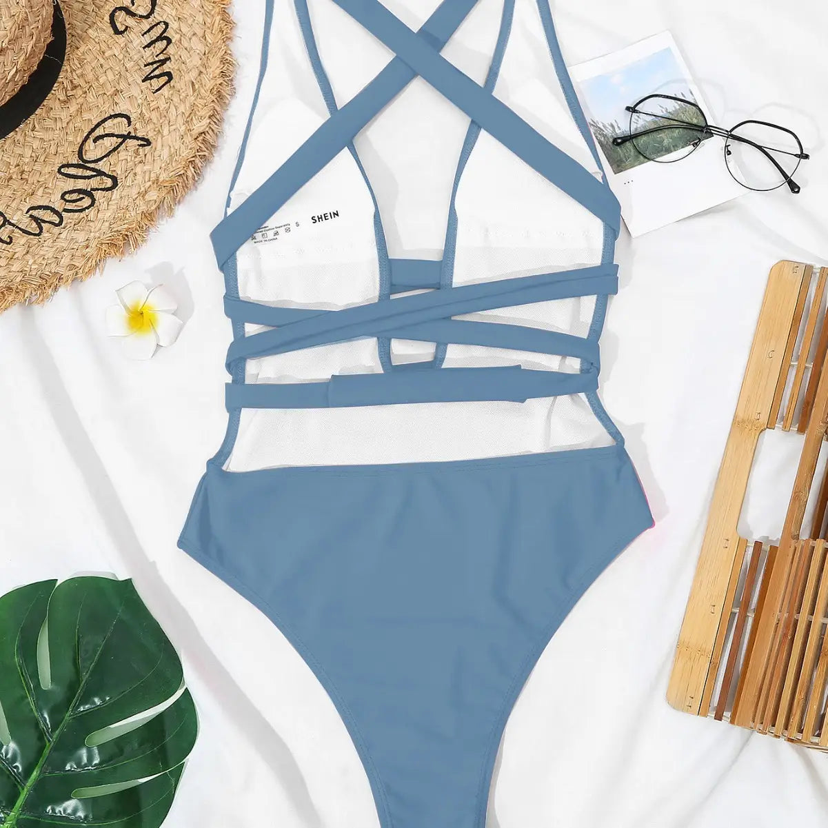 A stylish blue fashion pure color bikini swimsuit with a white underlay and crisscrossing straps in a black deep v neck design.