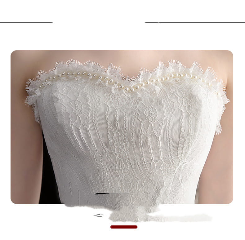 A delicate white lace strapless wedding dress bodice with a small trailing length and layered tulle featuring a row of small pearls along the sweetheart neckline.