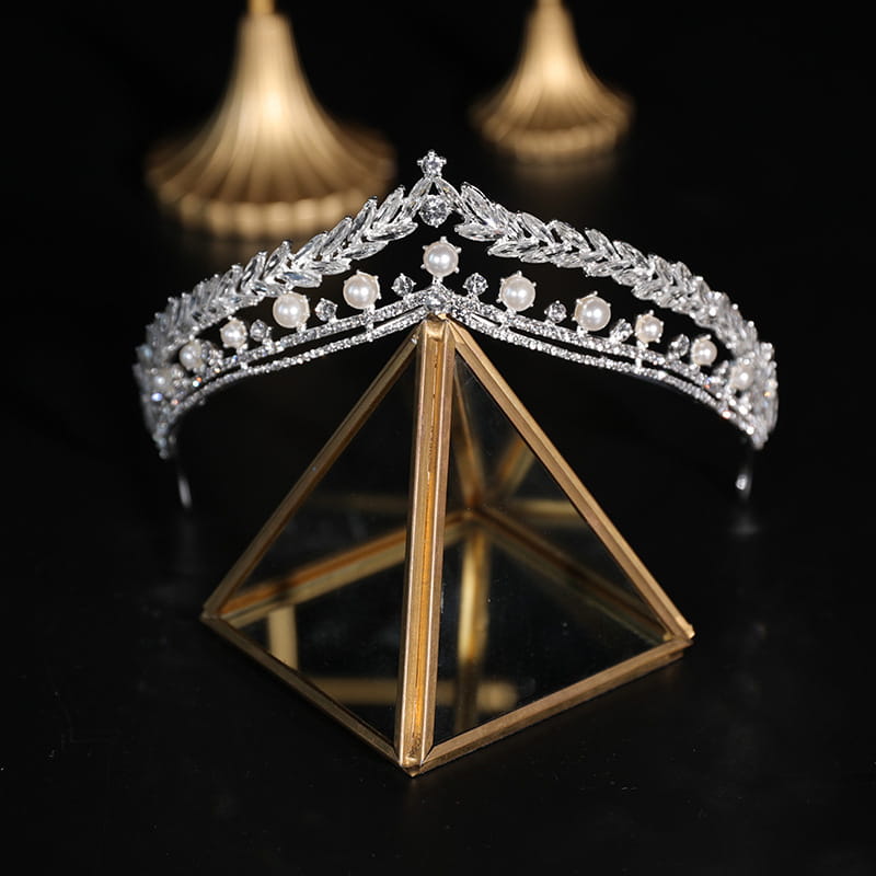 A silver starburst bridal crown baroque featuring an intricate leaf design adorned with sparkling crystals and round white baroque pearls.