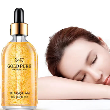 A clear glass bottle of 24k gold pure hyaluronic acid essence serum with gold-toned dropper cap and golden-yellow liquid