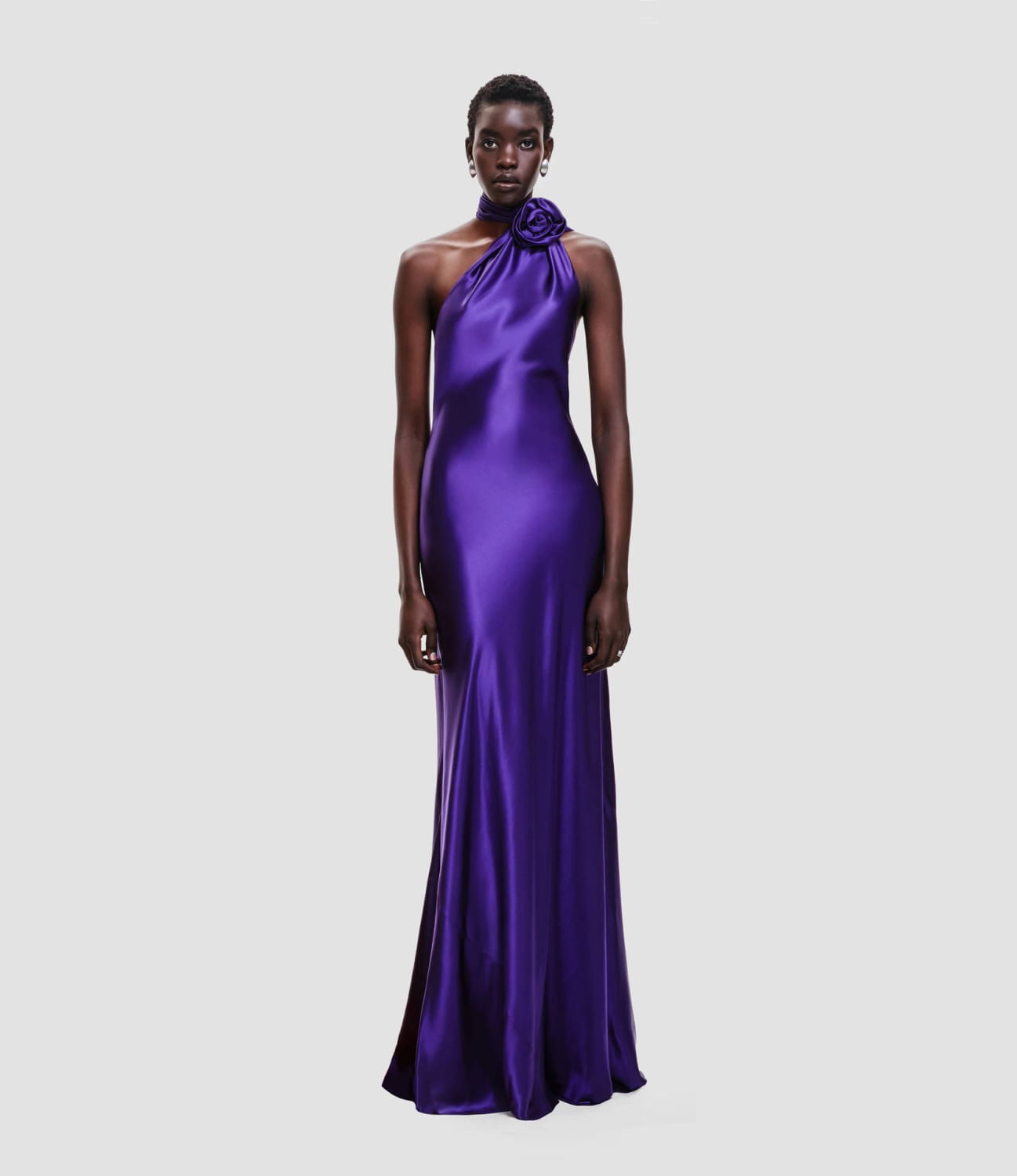 A sleek fitted high waist one-shoulder purple satin gown with a rose accent at the neckline in a high waist pure color design.