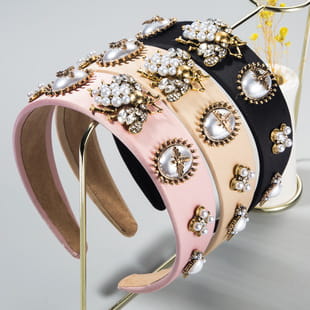 a set of three elegant baroque colorful headbands in soft pink and black satin with intricate gold-toned embellishments featuring sparkling gemstones and pearl-like accents