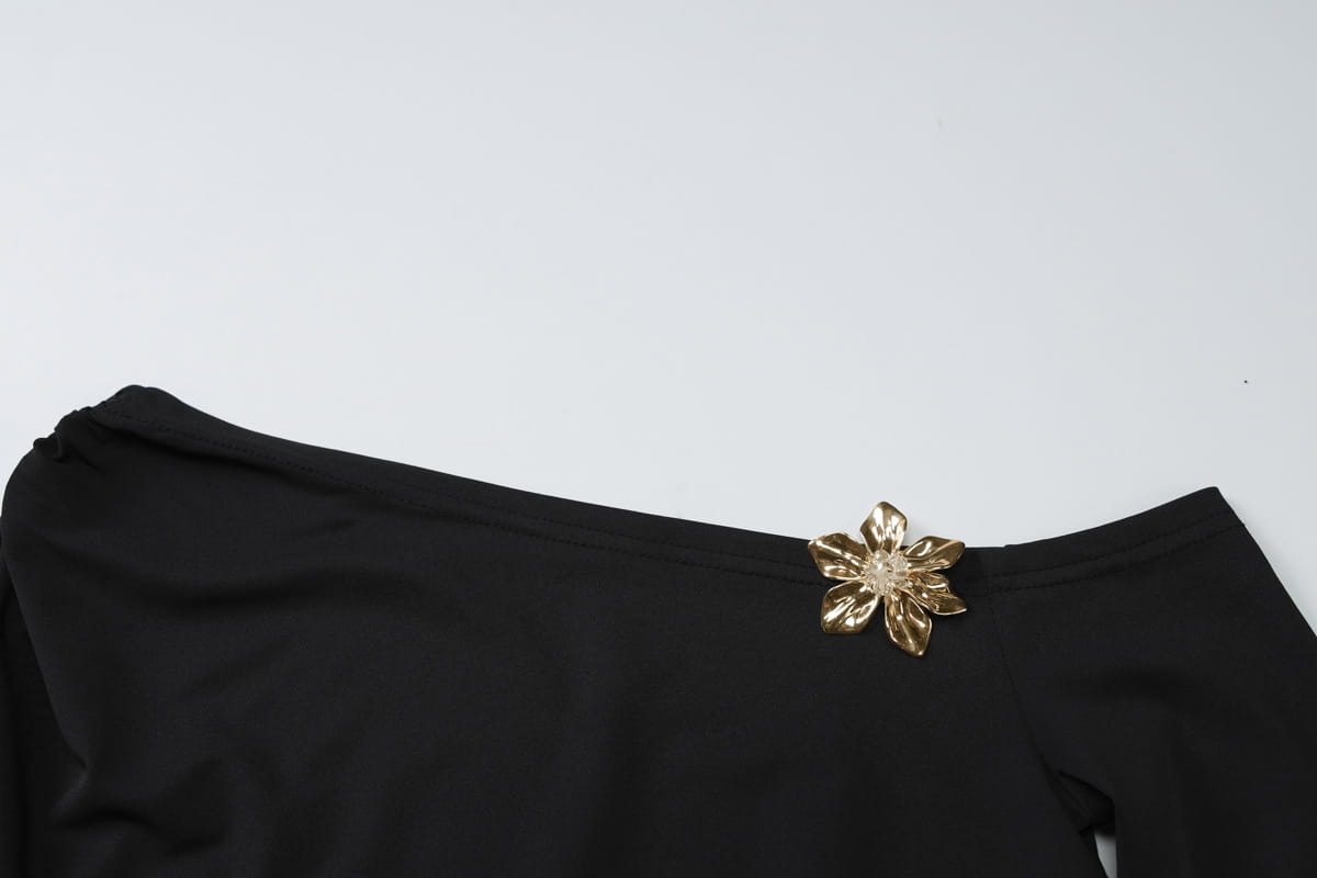 gold flower-shaped brooch with a sparkling center attached to a black sexy slim oblique shoulder floral mermaid dress.