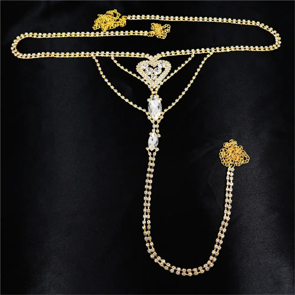 gold-toned heart rhinestone panty body jewelry features a body chain with a heart-shaped centerpiece and dangling teardrop crystals, complemented by a garter belt.