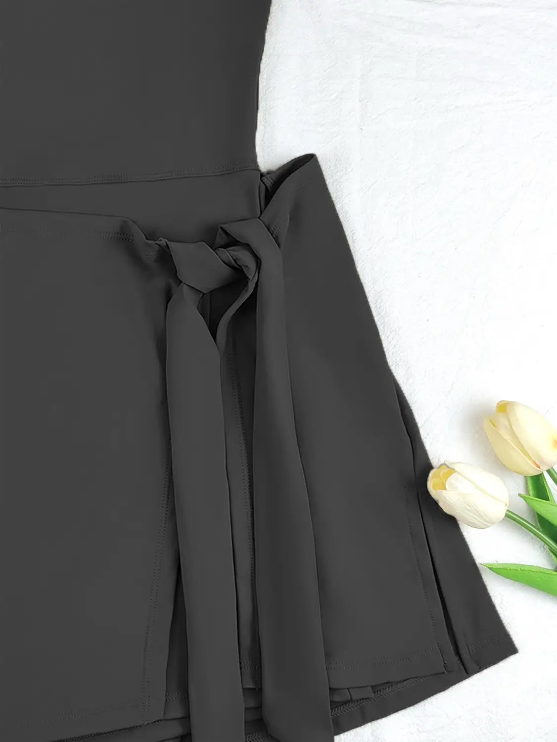 Black pleated yoga tennis skirt with a tied waistband and sleeveless side slit design for a comfortable tennis skirt sport dress.