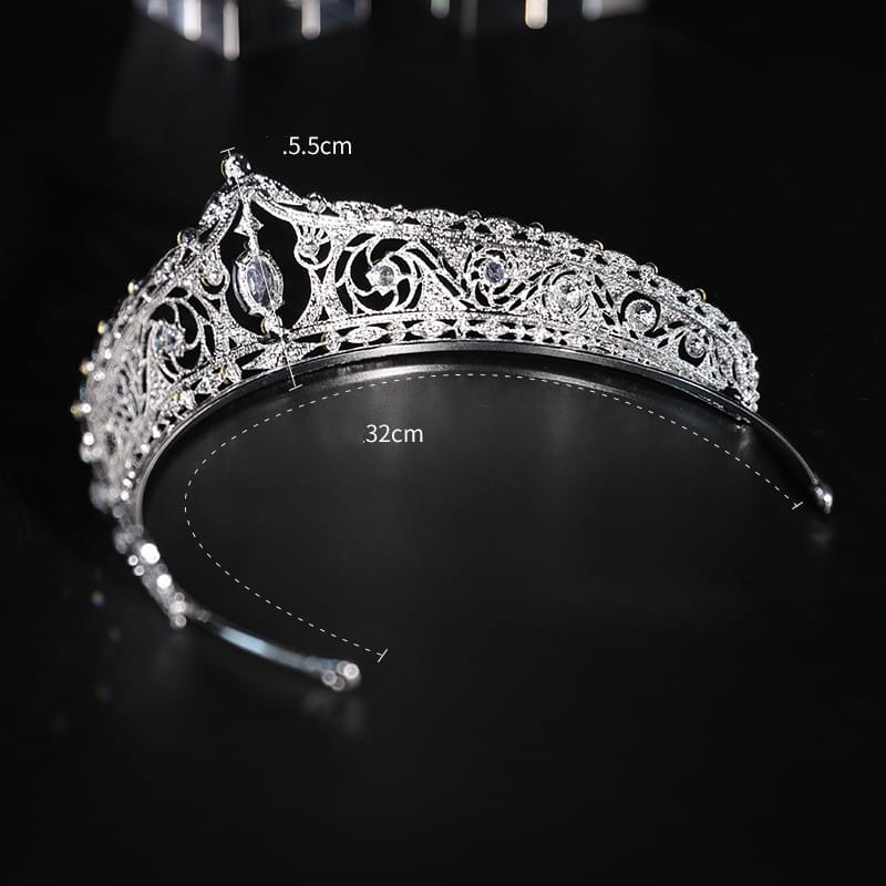 A sparkling silver filigree crystal European style bridal crown adorned with embedded crystals and a central oval gemstone, perfect for wedding makeup and bridal looks.